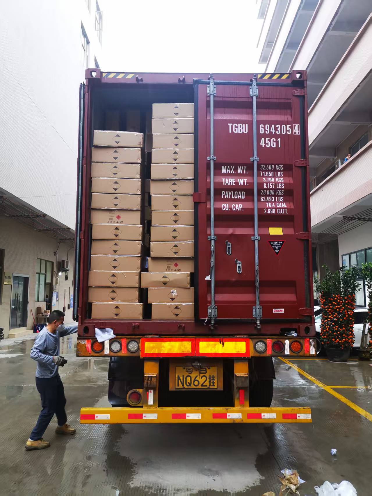 Worker guiding a container being loaded with cartons of skincare products